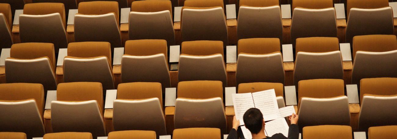 Man reading alone in an auditorium
