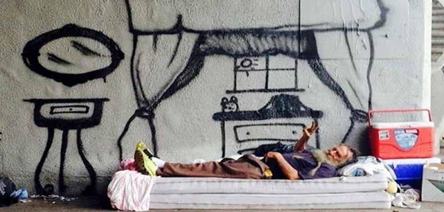 A homeless man lying in front of a graffiti room