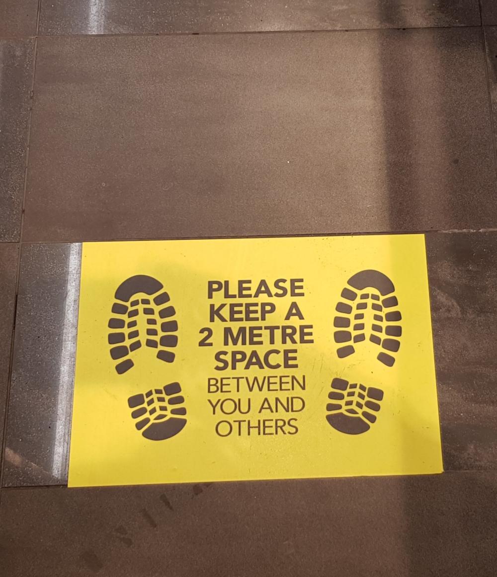 Sign on the floor: "Please keep 2 metre space between you and others"